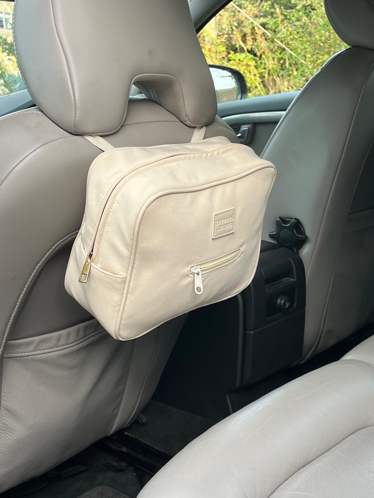 Beige car organizer attached to a car seat with a visible brand logo.